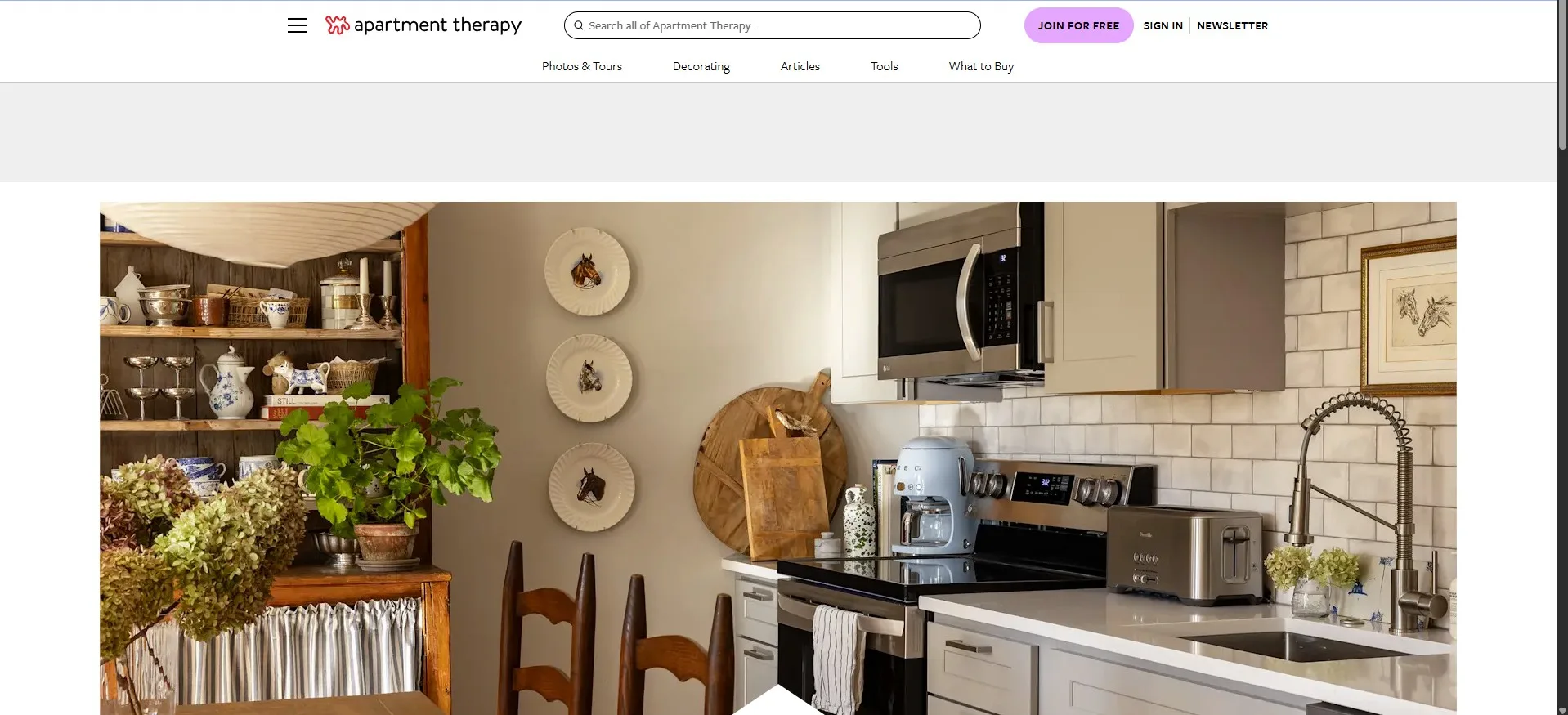 Apartment Therapy website showing a cozy kitchen decor with white subway tiles, a blue Smeg coffee maker, and rustic wooden shelves.