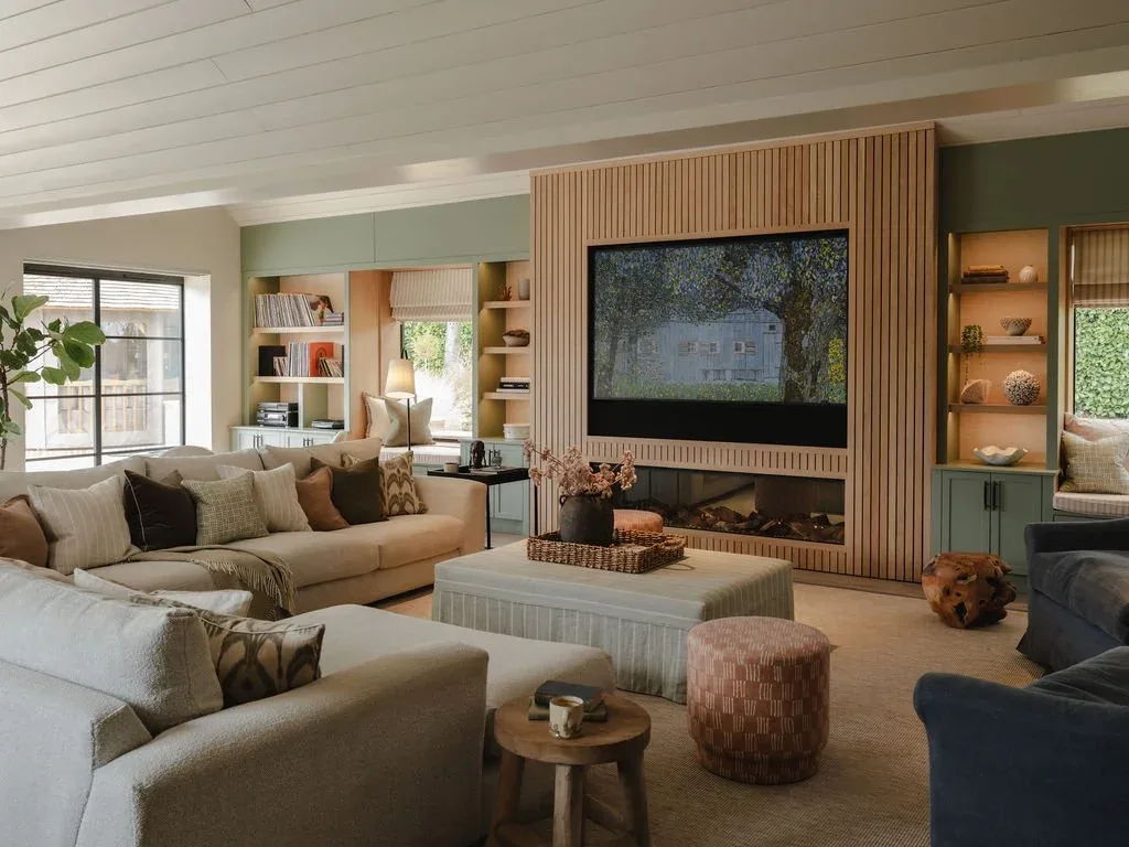 Modern living room with neutral tones, built-in shelving, large sectional sofa, and TV wall with wood